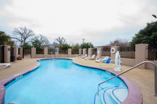 a large swimming pool with chairs and a fence at Comfort Suites University Drive in College Station