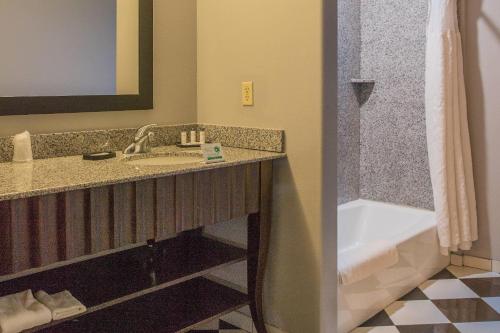a bathroom with a sink and a bath tub at Evangeline Downs Hotel, an Ascend Collection Hotel in Opelousas