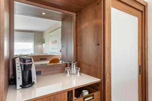 a kitchen with a mirror and a coffee maker on a counter at Cambria Hotel Plano - Richardson Garland in Richardson