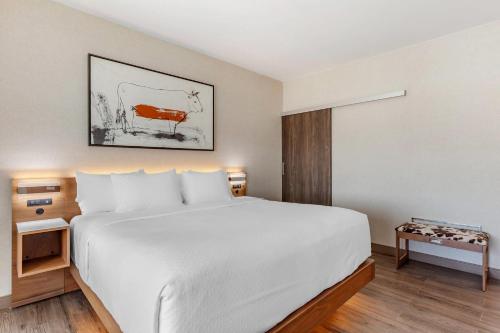 a hotel room with a bed and a picture of a cow at Cambria Hotel Plano - Richardson Garland in Richardson
