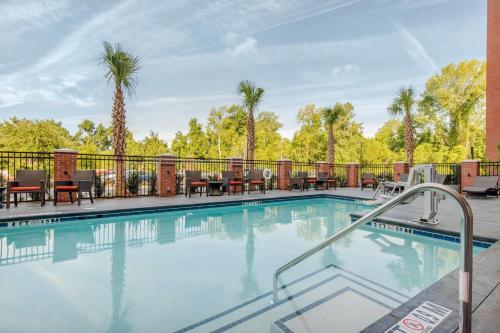 a swimming pool with patio furniture and palm trees at Cambria Hotel Mount Pleasant - Charleston in Charleston