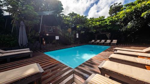 a swimming pool with chaise lounges on a wooden deck at Luxury Tented Village @ Urban Glamping in St Lucia