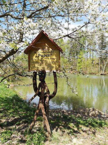 a statue of a person holding a bird house on its head at Chatka na břehu rybníka Pupek in Kohoutov