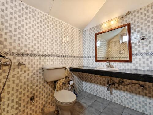 a bathroom with a toilet and a sink at Tripti Villas in Manāli
