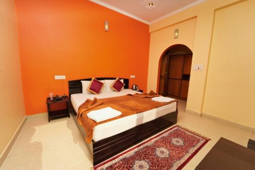 a bedroom with a bed with an orange wall at Shivalik River Retreat in Almora