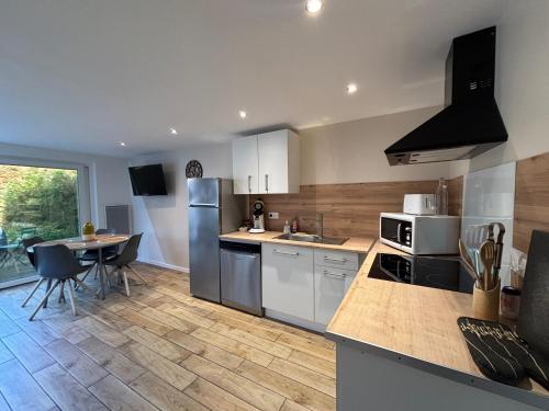 une cuisine avec des armoires blanches et une table à l'intérieur dans l'établissement Gîte Mer et Campagne, à Saint-Martin-Plage