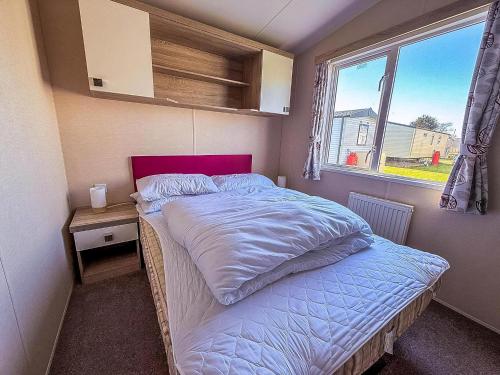 a small bedroom with a bed and a window at Modern 6 Berth Caravan With Free Wifi Nearby Pakefield Beach Ref 68028Cr in Lowestoft