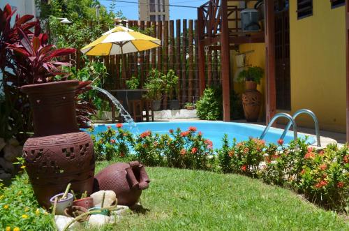 un jardín con una estatua de pájaro en el césped junto a una piscina en Pousada Coco Verde Natal, en Natal