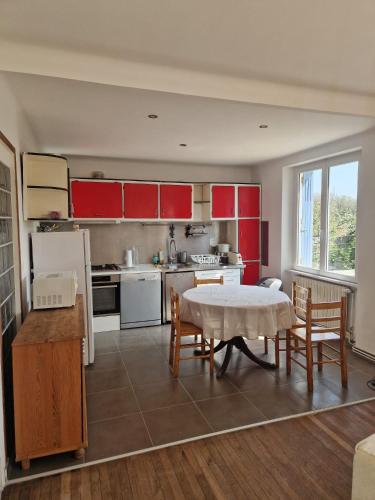 une cuisine avec des armoires rouges et une table et des chaises dans l'établissement Maison quartier calme, à 600m de la plage, jardin clos exposé sud, à Le Relecq-Kerhuon