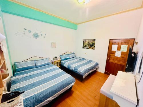 a bedroom with two beds and a desk and a table at Hostel Summer Light in Green Island