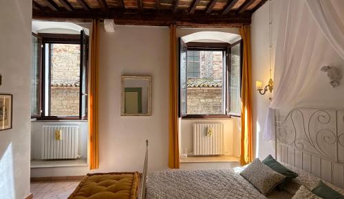 a bedroom with a bed and two windows at Santa Maria apartments in Todi