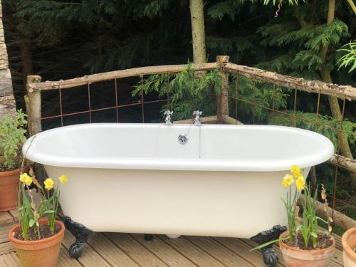 a bath tub sitting on a deck with plants at Old Oak Farm in Oakham