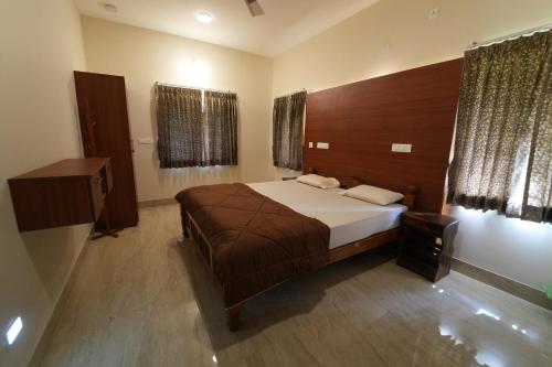 a bedroom with a large bed and two windows at Vamsi's Woodside in Yercaud
