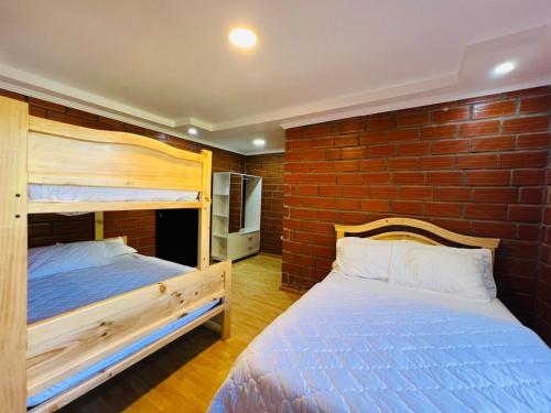 a bedroom with two bunk beds and a brick wall at Casa Brisa Volcánica in Baños