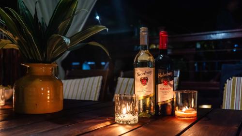 two bottles of wine on a wooden table with glasses at Luxury Tented Village @ Urban Glamping in St Lucia
