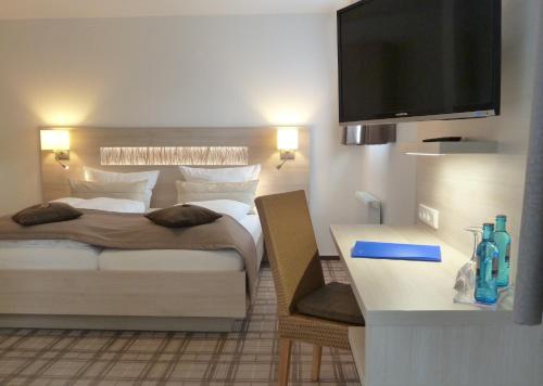 a bedroom with a bed and a flat screen tv at Hotel-Restaurant Goldenstedt in Delmenhorst