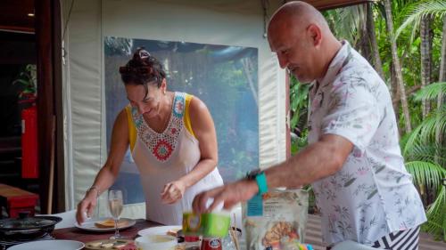 a man and a woman preparing food at a table at Luxury Tented Village @ Urban Glamping in St Lucia