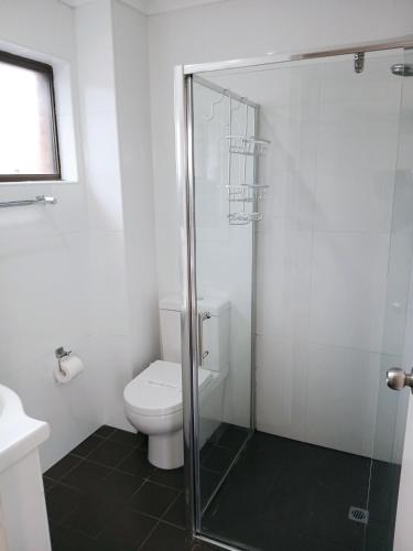 a bathroom with a toilet and a glass shower at Coastal Bay Motel in Coffs Harbour
