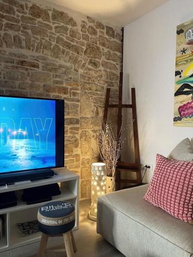 a living room with a tv and a brick wall at Bale Luxury House in Bale