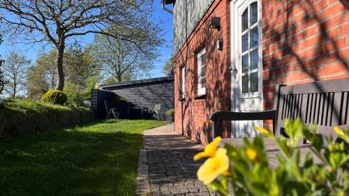 a red brick building with a window and a brick sidewalk at Ferienwohnung Sonne & Sauna in Sönnebüll