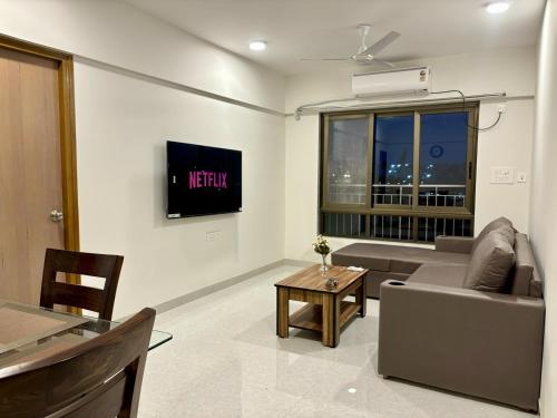 a living room with a couch and a tv at Vibrant 2 BHK Apartment Near Airport in Mumbai