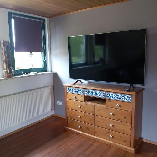 a television on a dresser in a room with two windows at Alfseeglück in Alfhausen