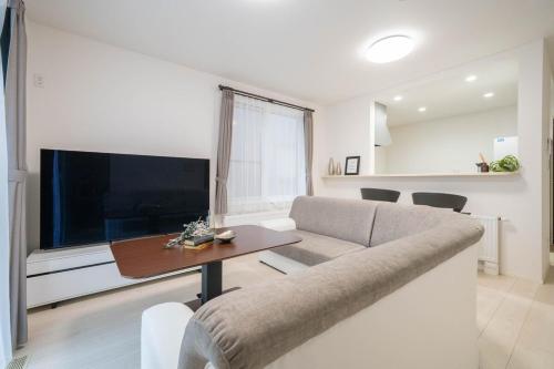 a living room with a couch and a table and a tv at Lumiere Enclave in Sapporo