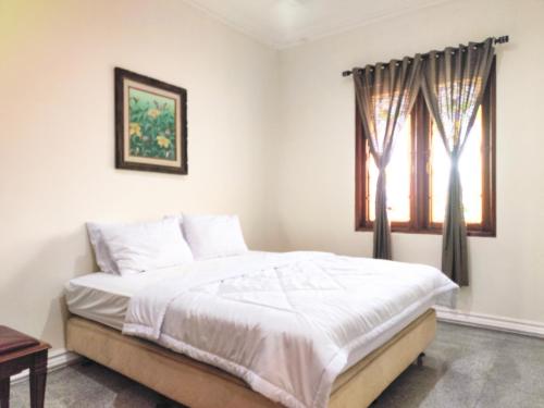 a bedroom with a bed and a window at Palma Villa Homestay Klaten in Kuwoso