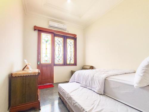 a bedroom with two beds and a door with a window at Palma Villa Homestay Klaten in Kuwoso