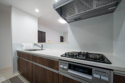 a kitchen with a stove top oven next to a sink at Lumiere Enclave in Sapporo