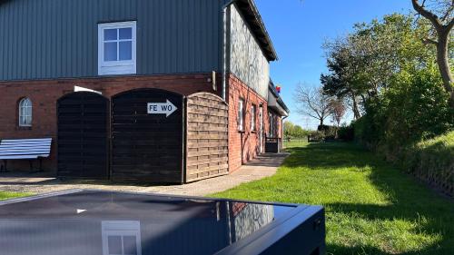 a brick building with a garage with a sign on it at Ferienwohnung Sonne & Sauna in Sönnebüll
