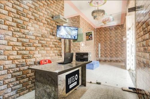 a office with a brick wall and a desk with a laptop at Shri LADDU GOPAL GUEST HOUSE in Chhatikara