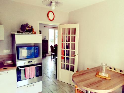 a kitchen with a table and a clock on the wall at Maison située aux confins de la Vallée du Loir in Le Lude
