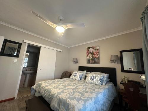 Un dormitorio con una cama y un ventilador de techo. en Peony Place, en Ciudad del Cabo