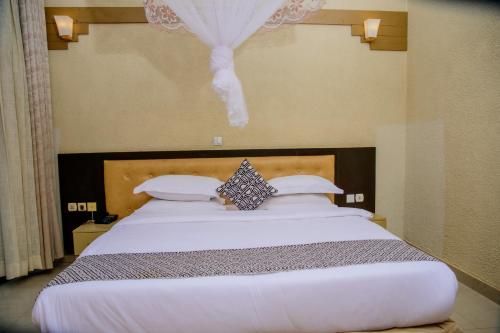 a bedroom with a large white bed with a headboard at Quality Inn Hotel Kigali in Kigali
