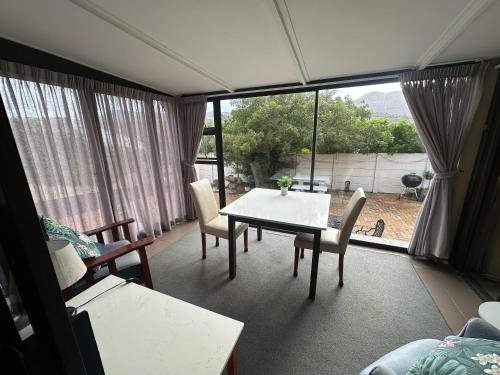Una sala de estar con una mesa y sillas y una ventana. en Peony Place, en Ciudad del Cabo