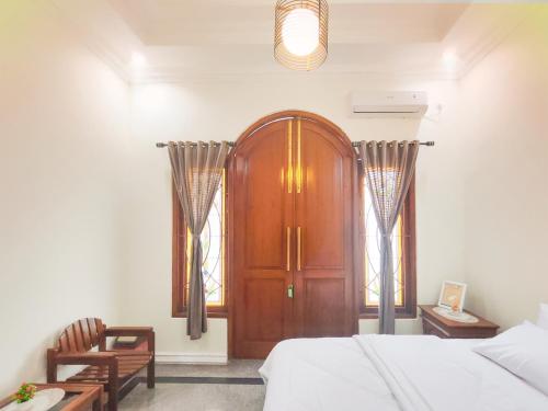 a bedroom with a wooden door and two windows at Palma Villa Homestay Klaten in Kuwoso