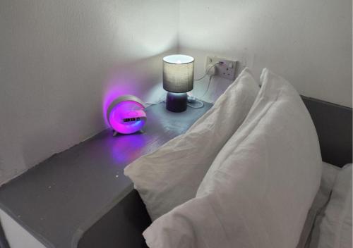 a bed with a table with a lamp on it at Comfortable 3 Bedrooms Leeds Beach House - Ideal for Family and Contractors - Free WIFI, Projector in bedroom and Free Parking for 2 cars in Killingbeck