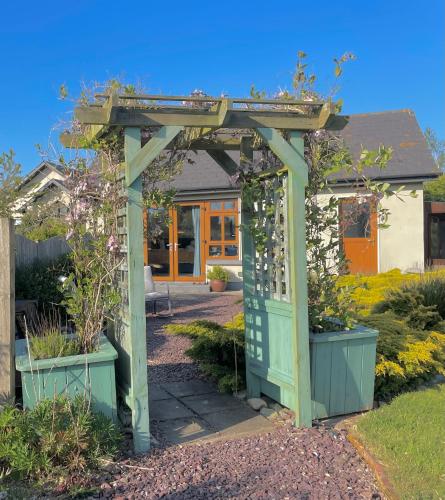 a green pergola in a garden with plants at The Conifers Studio Apartment With Private Garden in Wexford