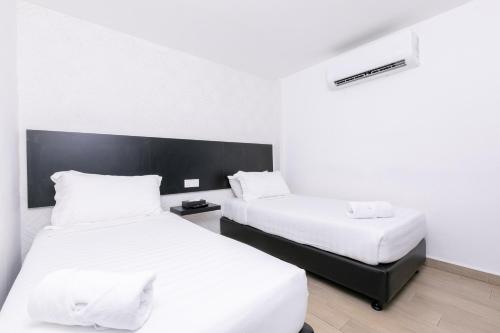 two beds in a hotel room with white sheets at E Hotel Kulim in Kulim