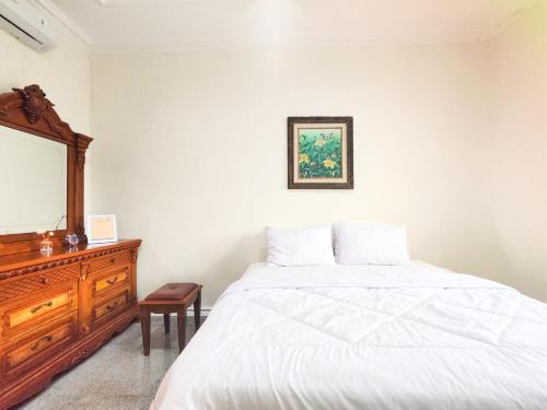 a bedroom with a bed and a dresser and a mirror at Palma Villa Homestay Klaten in Kuwoso