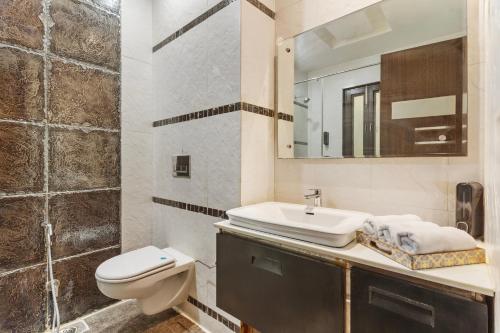 a bathroom with a sink and a toilet and a mirror at MIRANDA by AKAMA HOMES in Noida