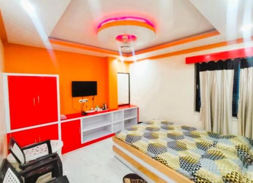 a bedroom with orange walls and a bed and a tv at Hotel Anurag Palace In Agartala in Agartala