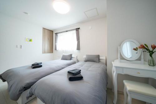 two beds in a room with a mirror and a desk at Lumiere Vista in Sapporo