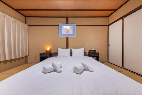 a bedroom with a large white bed with two white towels at Shiki Homes HARU in Kyoto