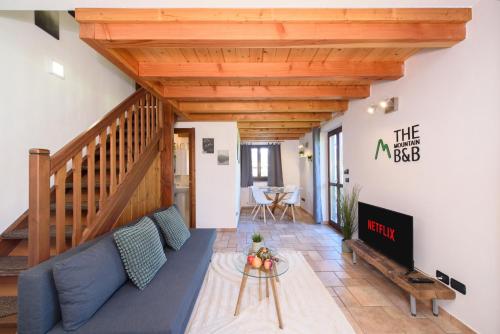 奥斯塔"The Mountain B&B" - SKI, MTB & BEAUTIFUL VIEW - PRIVATE PARKING的客厅设有蓝色的沙发和木制天花板。