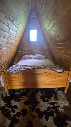 a bed in a wooden room with a window at Cabana A-frame Moon Predelut in Predeluţ