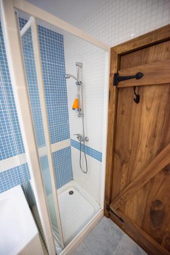 Un baño con ducha con puerta de madera. en A Lagosta Perdida, en Montezinho