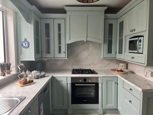 a kitchen with white cabinets and a stove top oven at Luxury 4 bedroom lodge in Doolin in Doolin