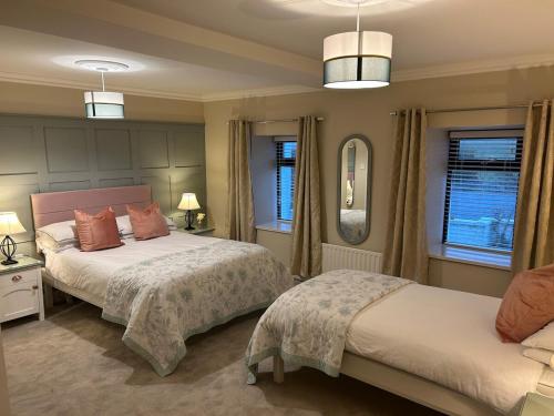 a bedroom with two beds and two windows at Luxury 4 bedroom lodge in Doolin in Doolin